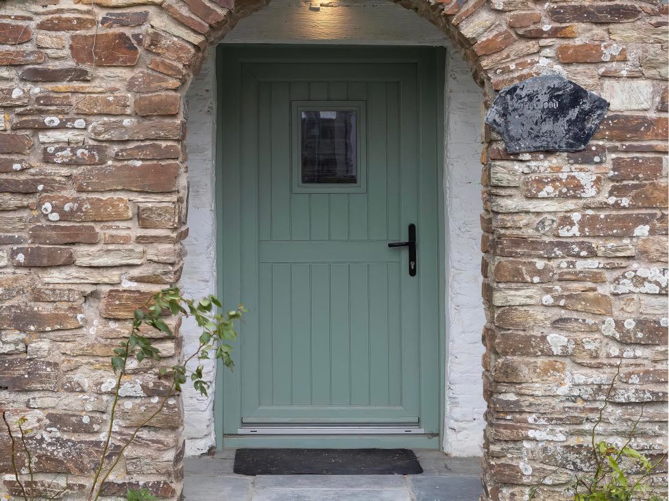 An entrance with a green door and stone wall at Rose Cottage in Wadebridge