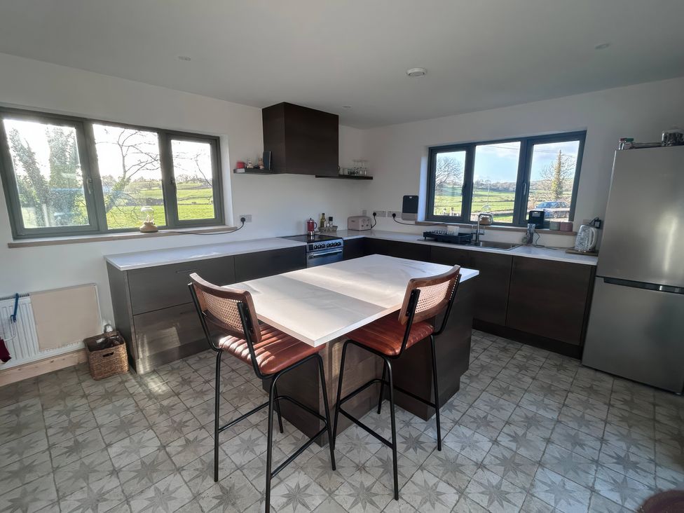 A kitchen with a kitchen island and stools at Knocknanuss