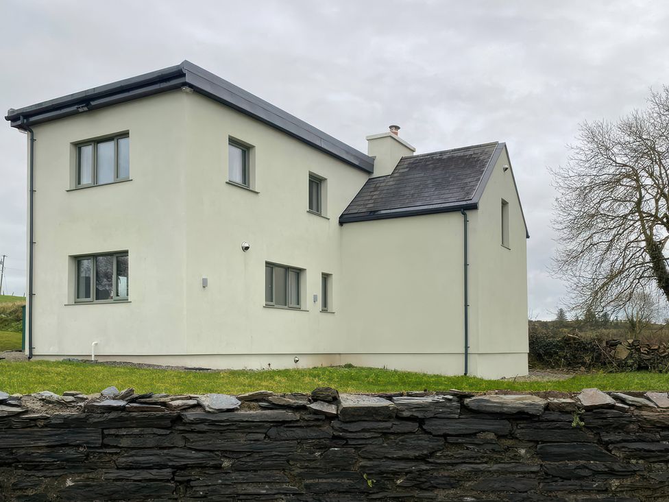 A house with a stone wall and grass area at Knocknanuss in 