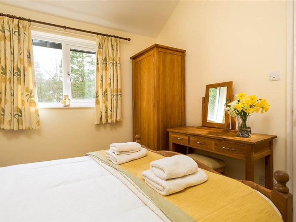 A bedroom with a bed and wardrobe at 2 Riverside Cottages Ambleside