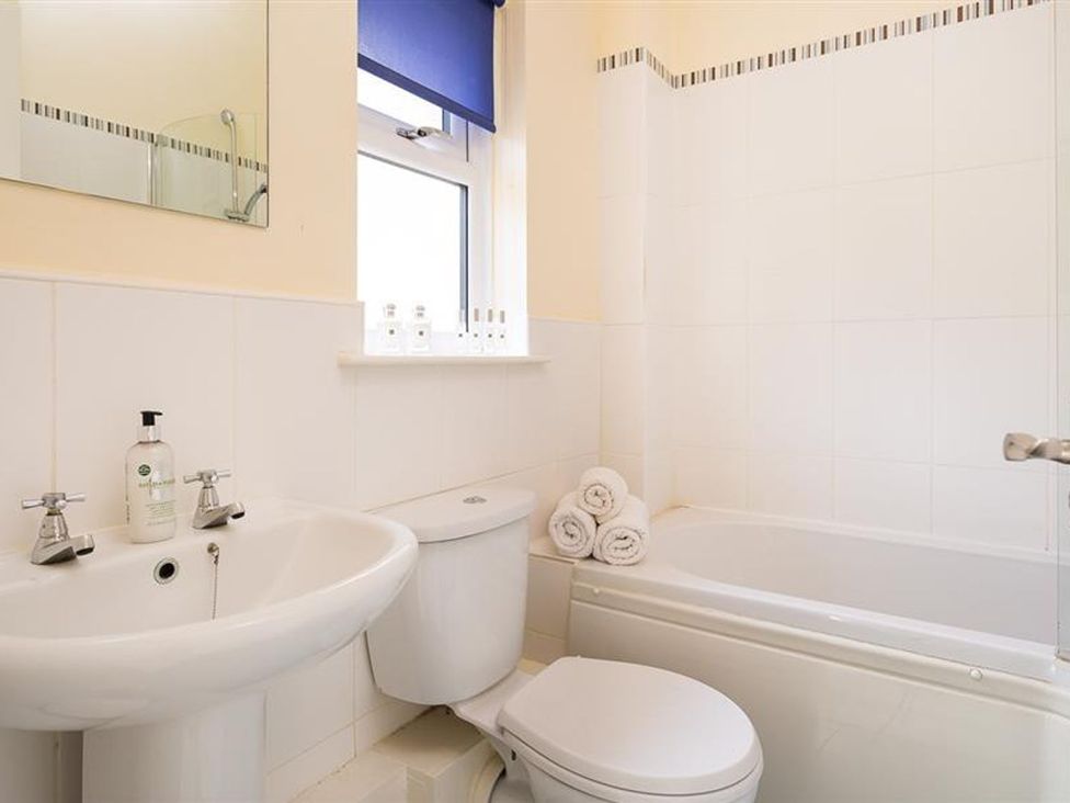 A bathroom with a wash basin, toilet, and bath at 2 Riverside Cottages in Ambleside