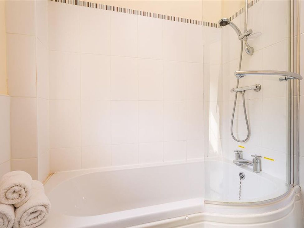 A bathroom with a bathtub and shower at 2 Riverside Cottages Ambleside