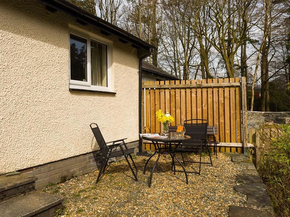 A patio area with chairs and a table at 2 Riverside Cottages Ambleside