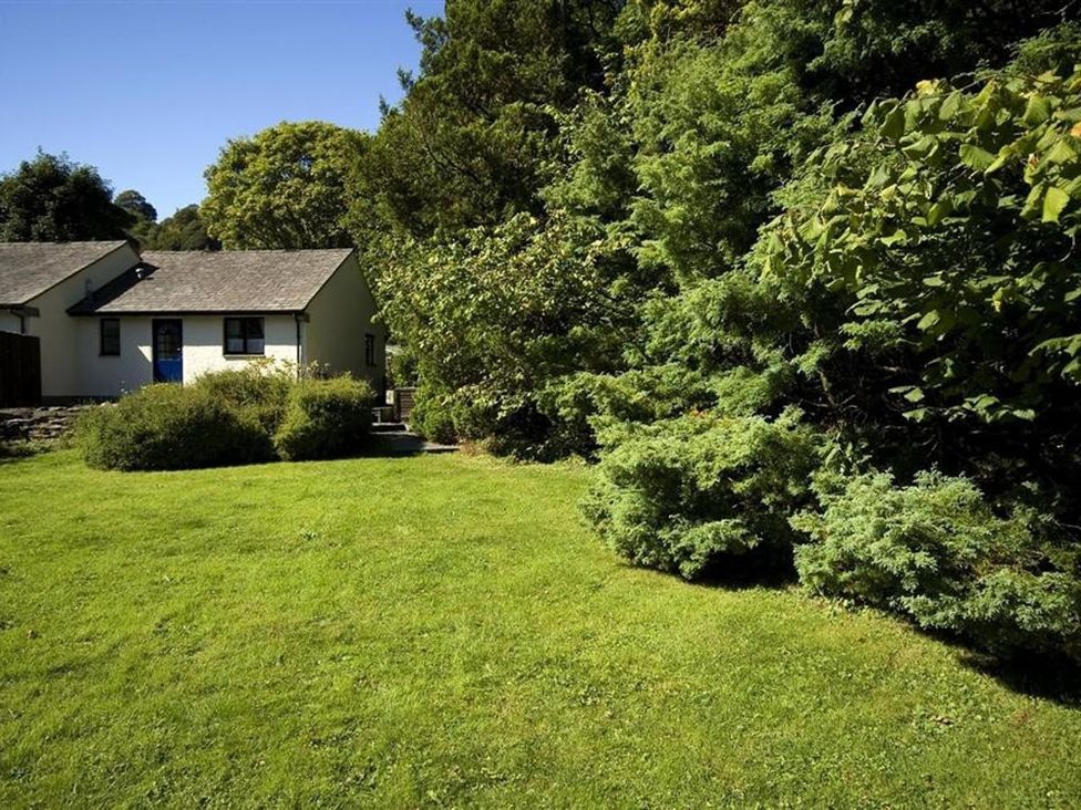 A house with trees and a grassy area at 2 Riverside Cottages Ambleside
