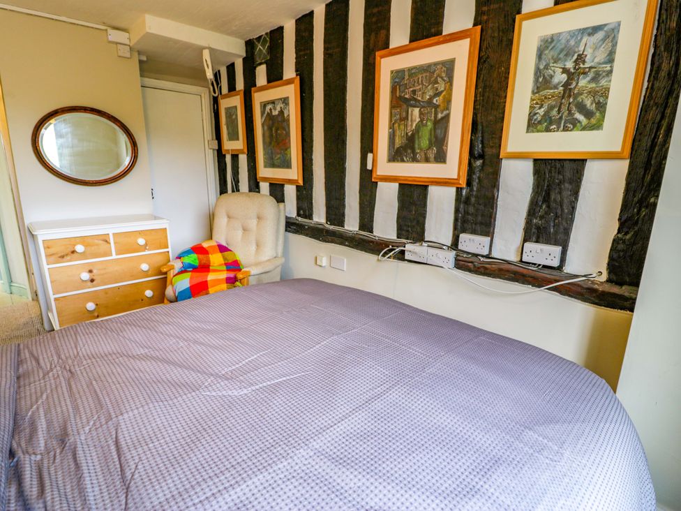 A bedroom with a bed, drawers, and paintings at Bryn Dwr in Llangollen