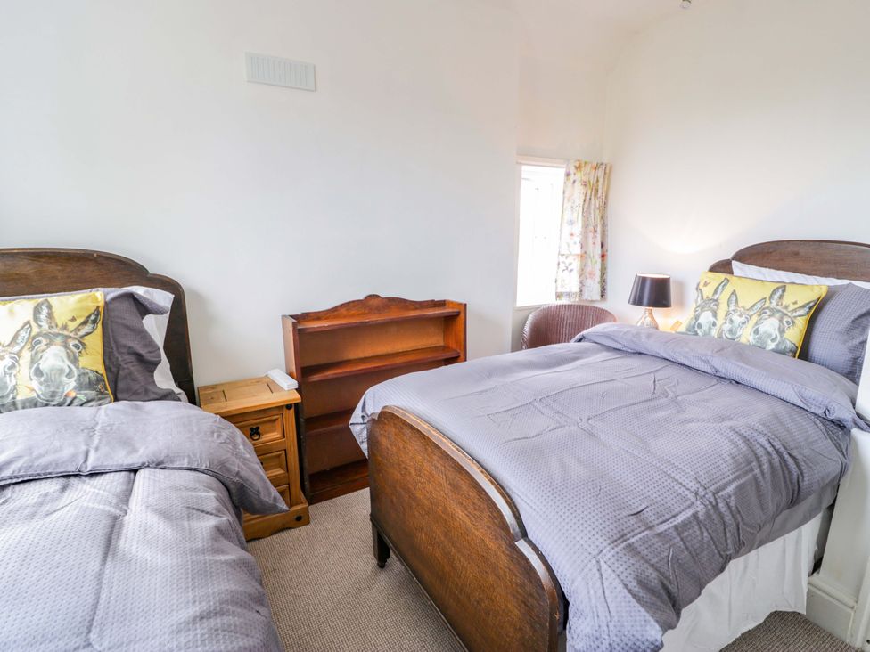 A bedroom with two beds and a bookshelf at Bryn Dwr in Llangollen