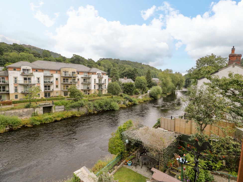 A view of a river with surrounding buildings and greenery at Bryn Dwr in Llangollen