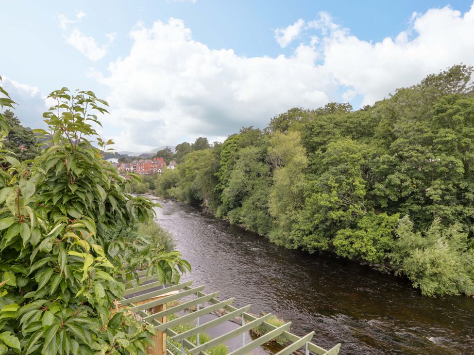 A river surrounded by trees with a view of buildings at Bryn Dwr in Llangollen