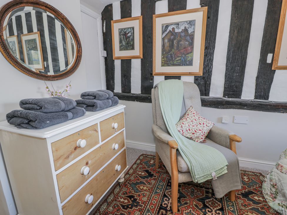 A sitting room with a chair and towels on a chest of drawers at Bryn Dwr in Llangollen