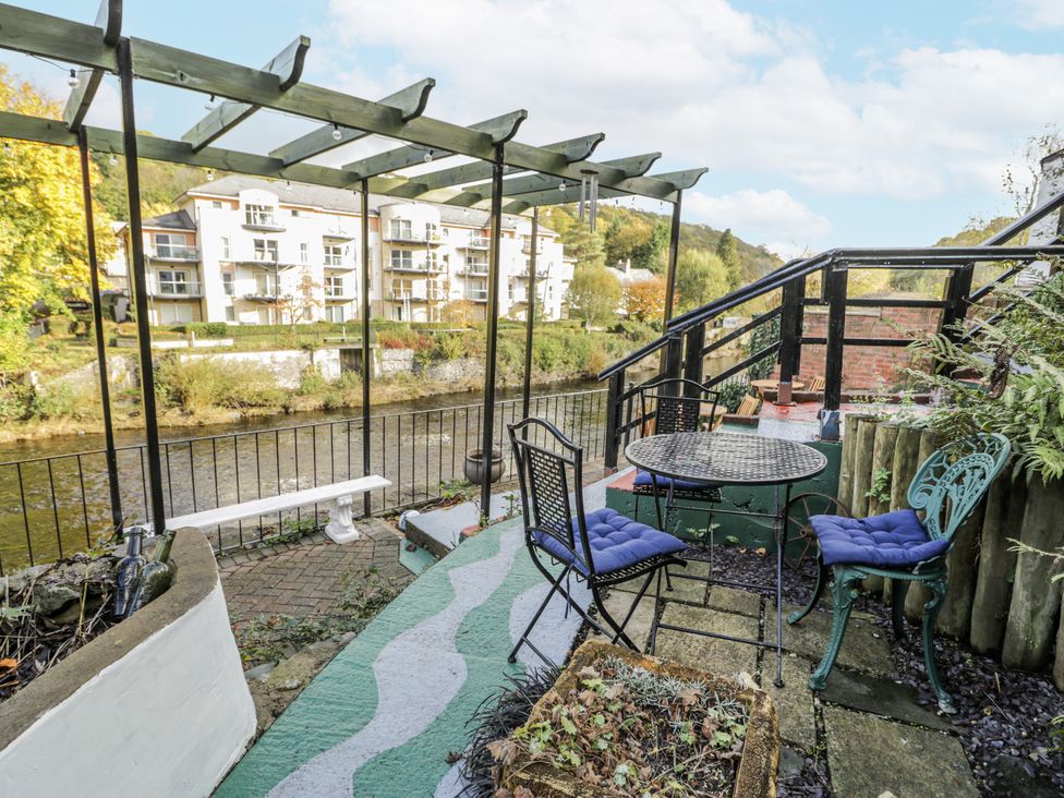 An outdoor seating area with a table and chairs by the river at Bryn Dwr in Llangollen