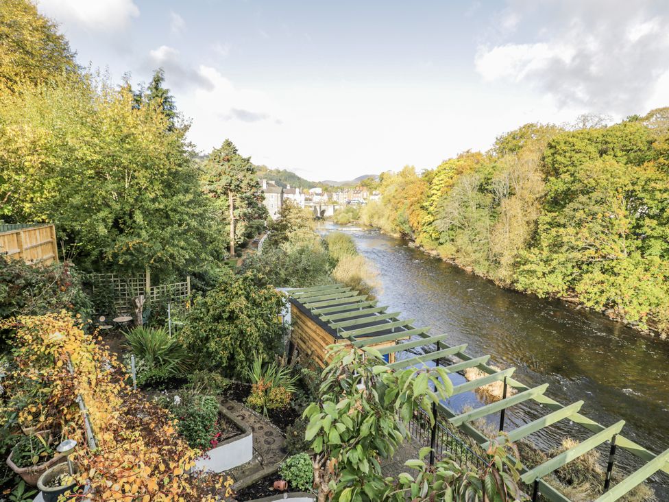 A garden with a view of a river and trees at Bryn Dwr in Llangollen