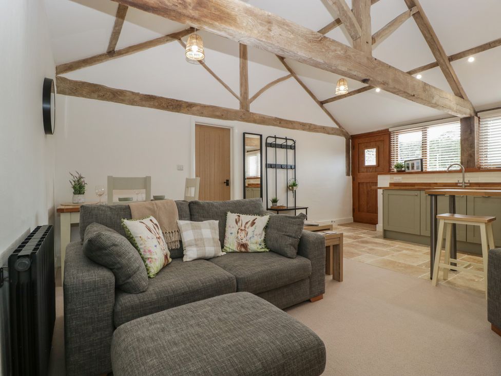A living room with a sofa and kitchen area at The Old Cart Shed in Gorsley