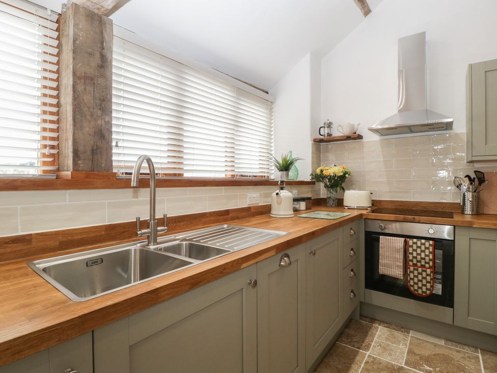 A kitchen with a sink, cabinets, oven, and window at The Old Cart Shed, Gorsley