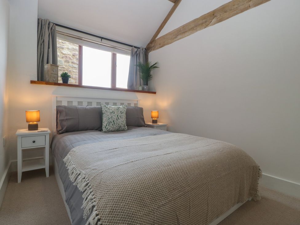 A bedroom with a bed and nightstands at The Old Cart Shed in Gorsley
