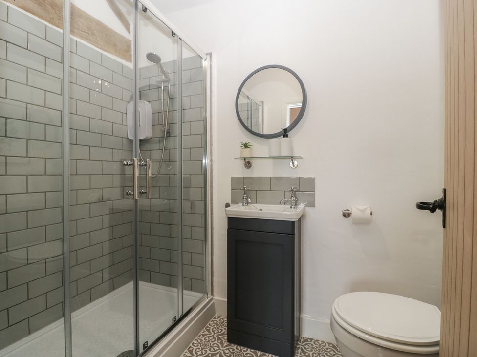 A bathroom with a shower, toilet, and sink at The Old Cart Shed in Gorsley
