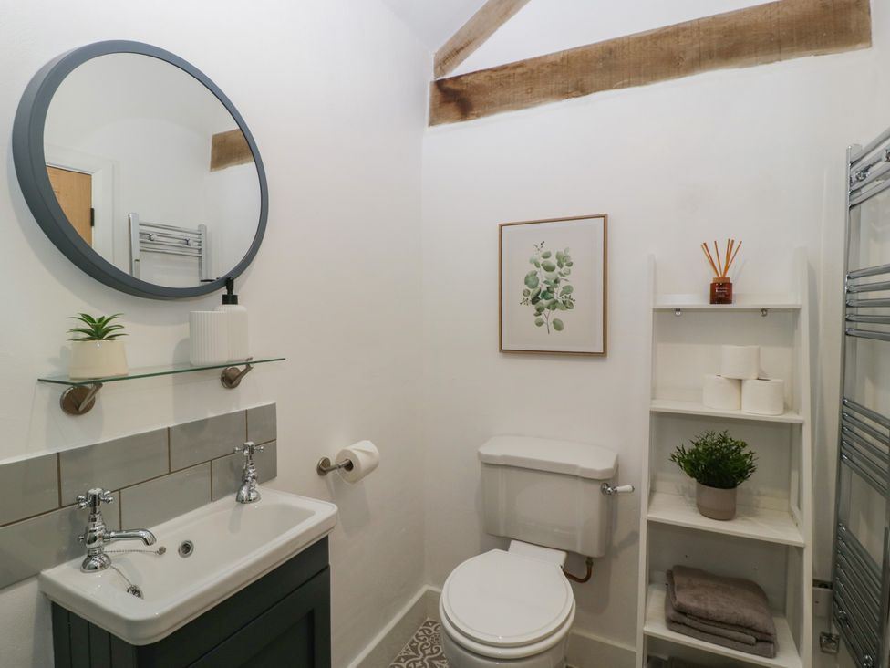A bathroom with sink, toilet, and decorative shelf at The Old Cart Shed in Gorsley