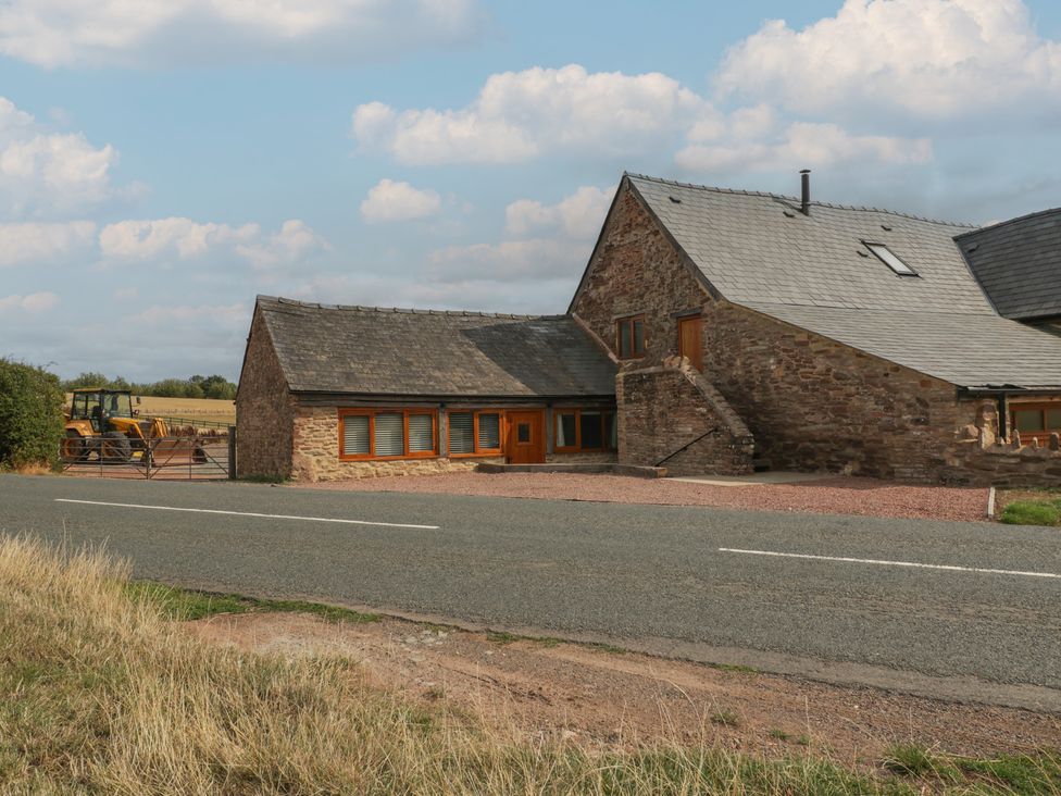 An exterior view of a building with a tractor and gate at The Old Cart Shed in Gorsley