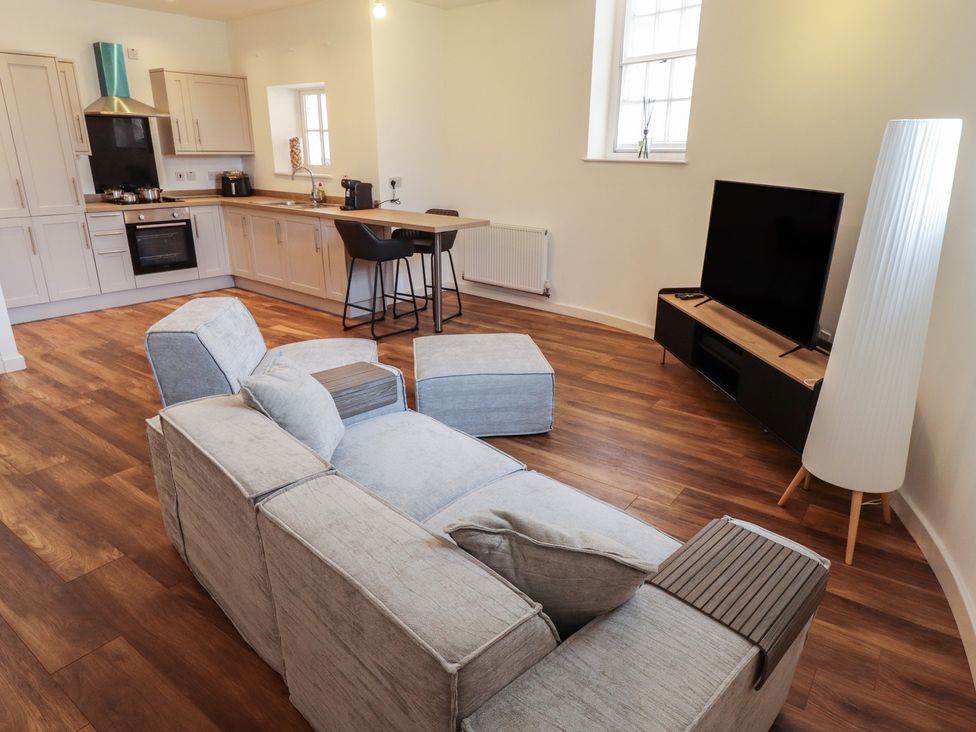 A living room with a sofa and kitchen area at 10c King Street in King's Lynn