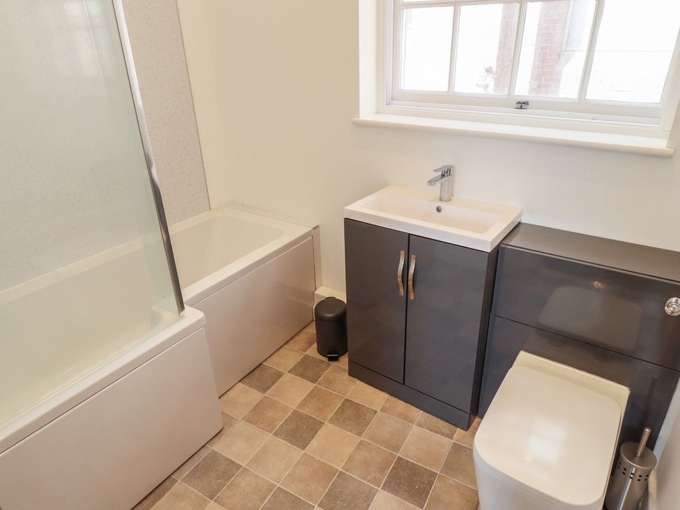 A bathroom featuring a bathtub, sink, toilet, and cabinet at 10c King Street, King's Lynn