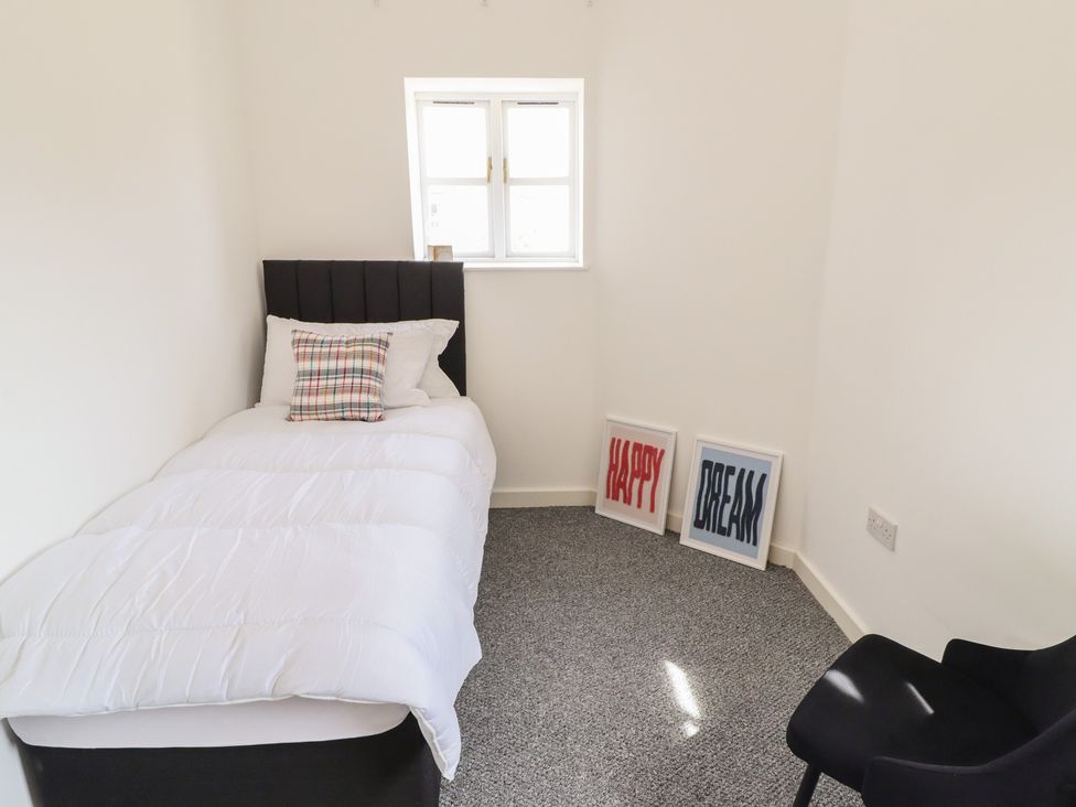 A bedroom with a single bed and framed wall art at 10c King Street in King's Lynn