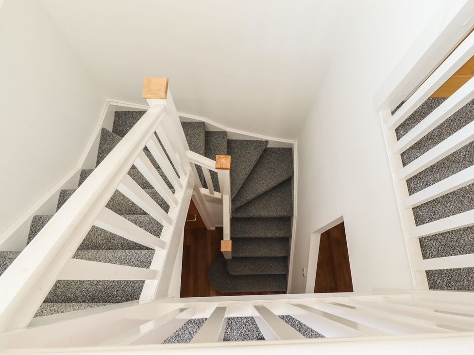 A staircase with carpeted steps and wooden handrail at 10c King Street in King's Lynn
