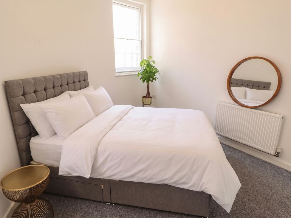 A bedroom with a bed, mirror, and plant at 10c King Street in King's Lynn