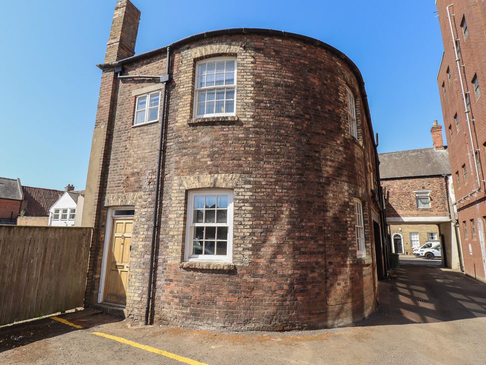 A curved brick building with windows and a door at Corner House in King's Lynn