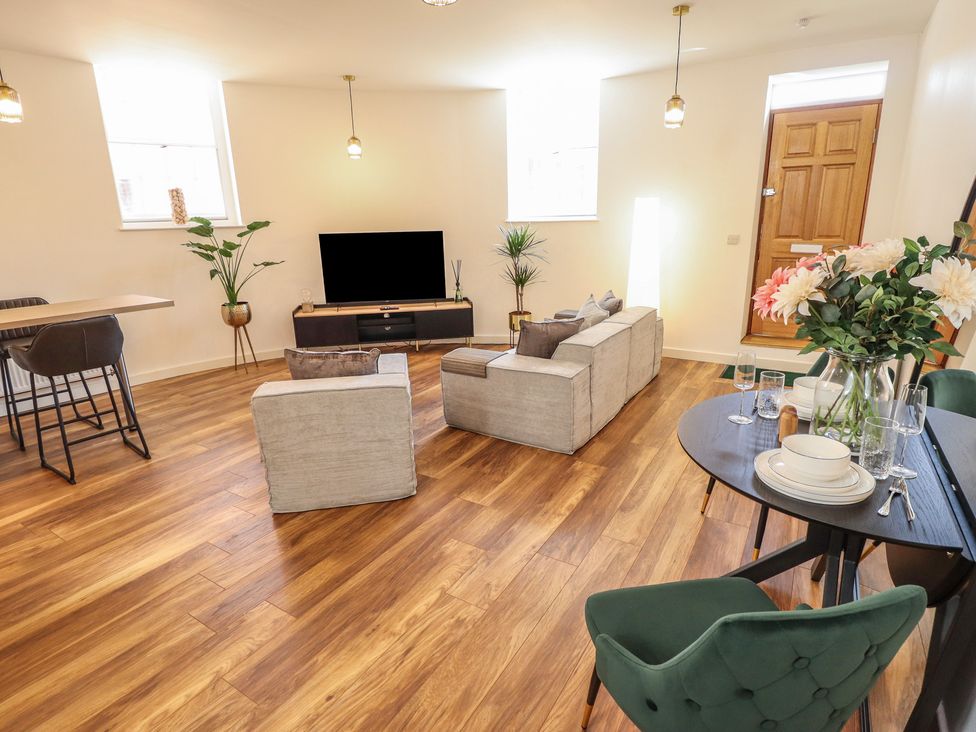A living room with a sofa, television and dining area at Corner House in King's Lynn