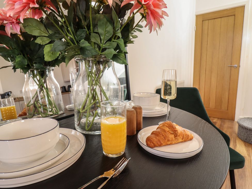 A dining table with flowers, juice, and croissant at Corner House in King's Lynn