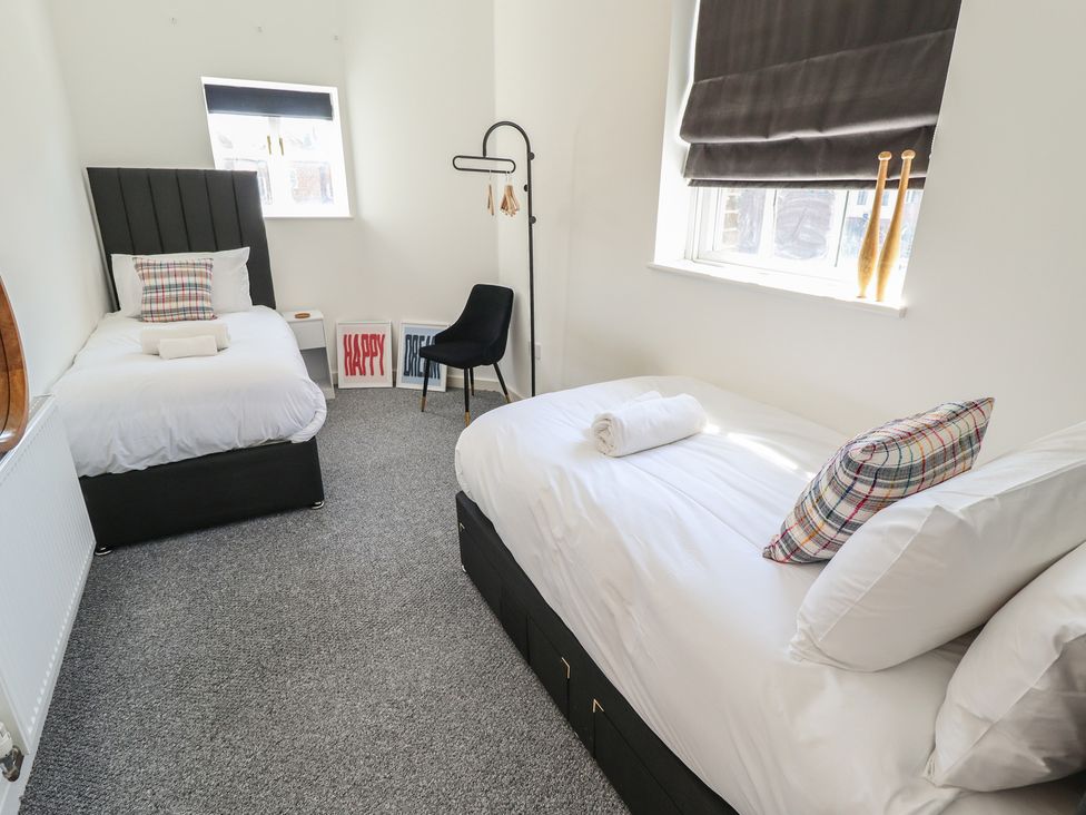 A bedroom with two beds and decorative items at Corner House in King's Lynn