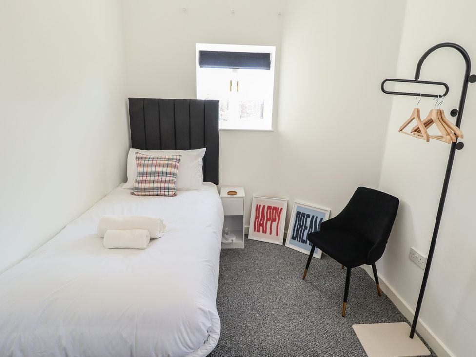 A bedroom with a single bed and a chair at Corner House in King's Lynn