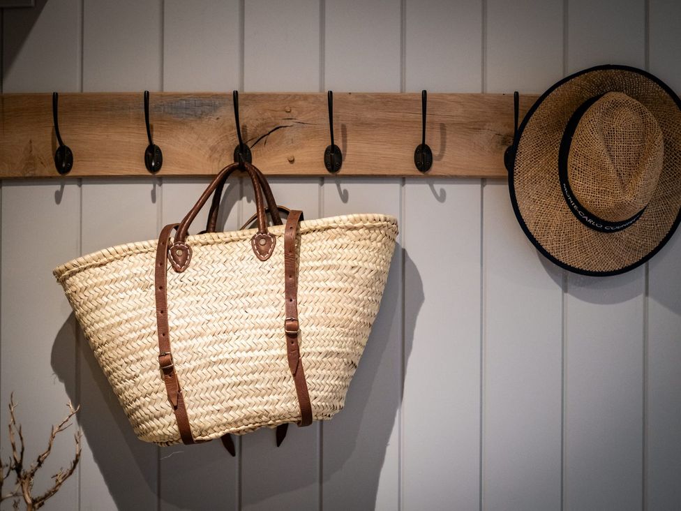 A basket and a hat hanging on hooks in the entryway at Calm Waters Luxury Beach House in Bridlington