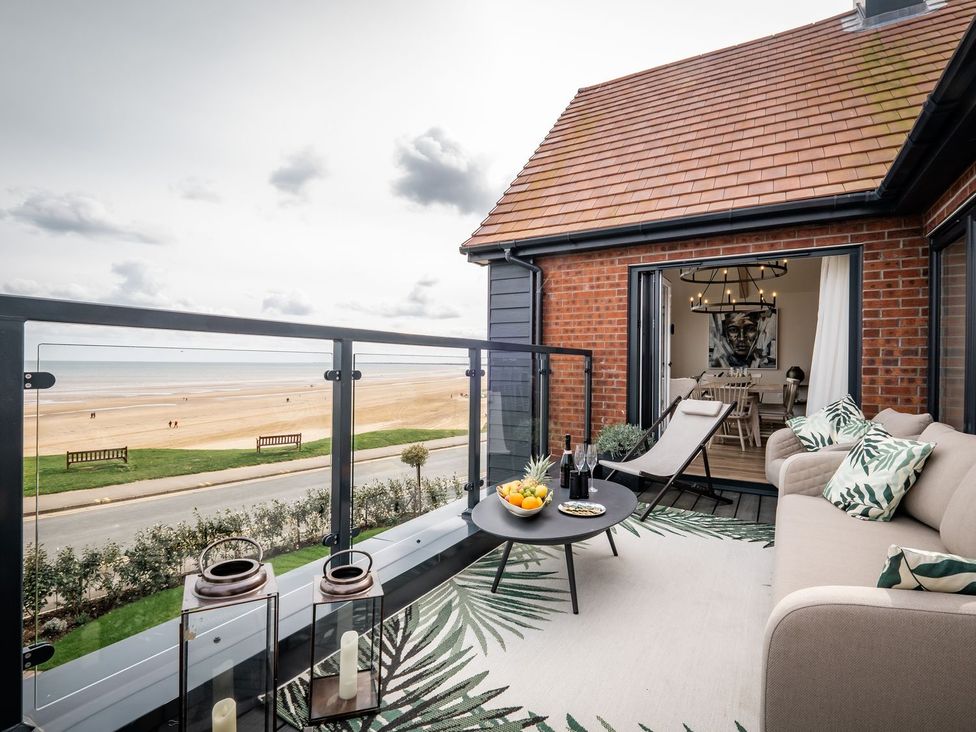 A balcony with seating and a view of the beach at Calm Waters Luxury Beach House in Bridlington