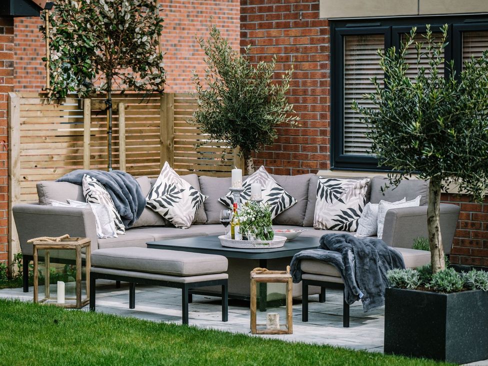 A garden with an outdoor sofa and coffee table at Calm Waters Luxury Beach House in Bridlington