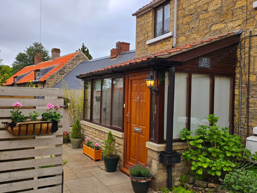 An entrance featuring a wooden door and planters at Minns Cottage in Snainton