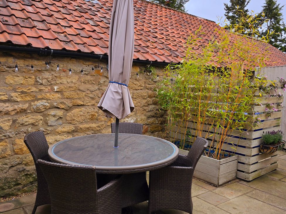 An outdoor seating area with a table and chairs at Minns Cottage Snainton