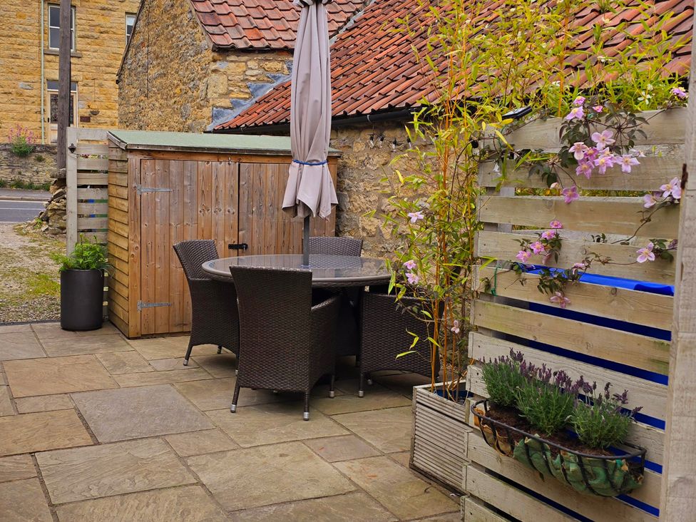 A garden with a table and chairs under an umbrella at Minns Cottage in Snainton