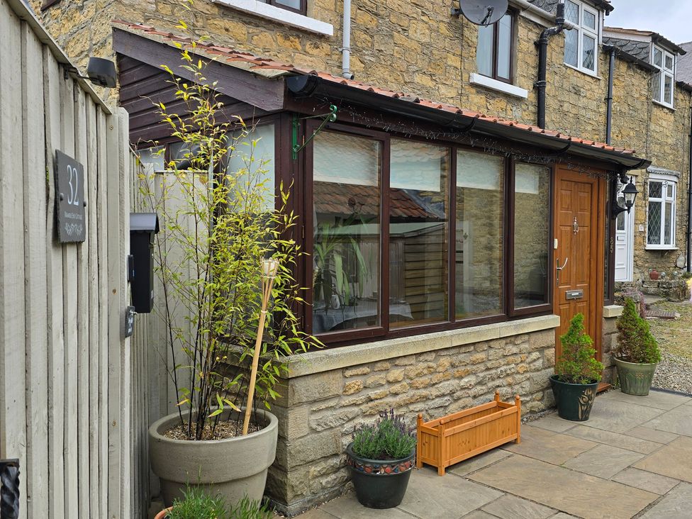 An entrance with a wooden door and planter at Minns Cottage in Snainton