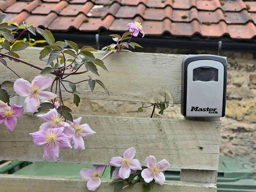 A lockbox on a wooden fence with flowers in an outdoor area at Minns Cottage in Snainton