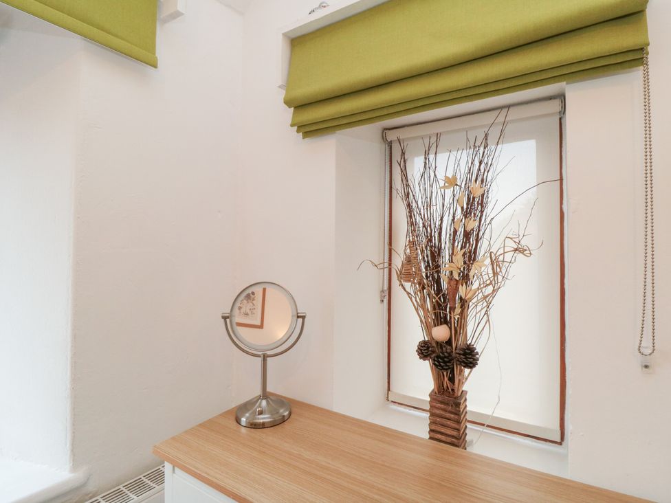 A room with a mirror and decorative arrangement on a wooden table at Minn's Cottage in Snainton