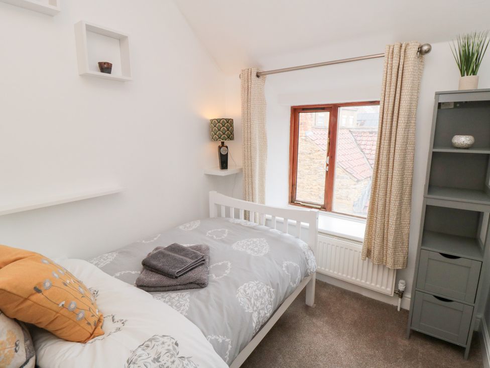 A bedroom with a bed and lamp at Minn's Cottage Snainton