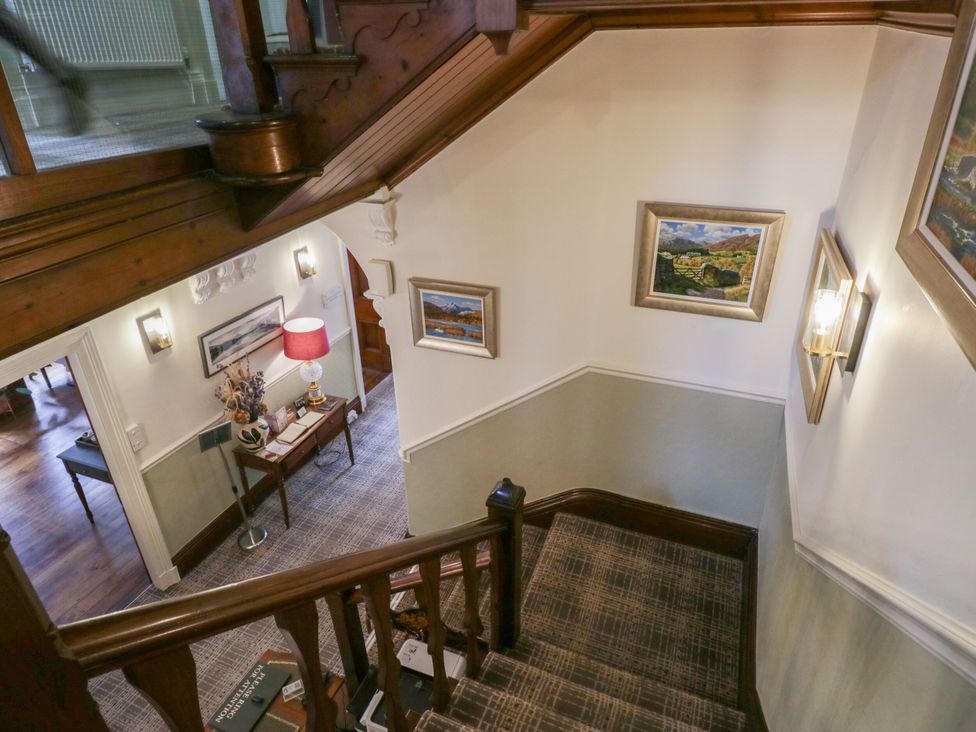 A staircase with wall lamps and a table at Shelley in Ambleside