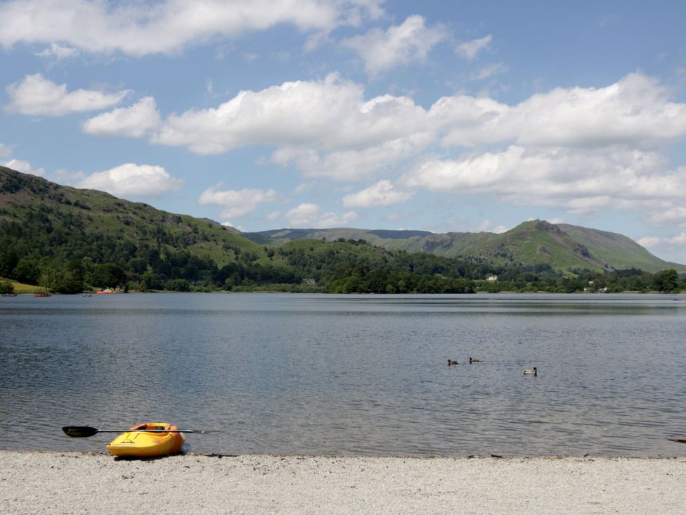 A kayak on the shore of a lake with ducks swimming at Shelley in Ambleside