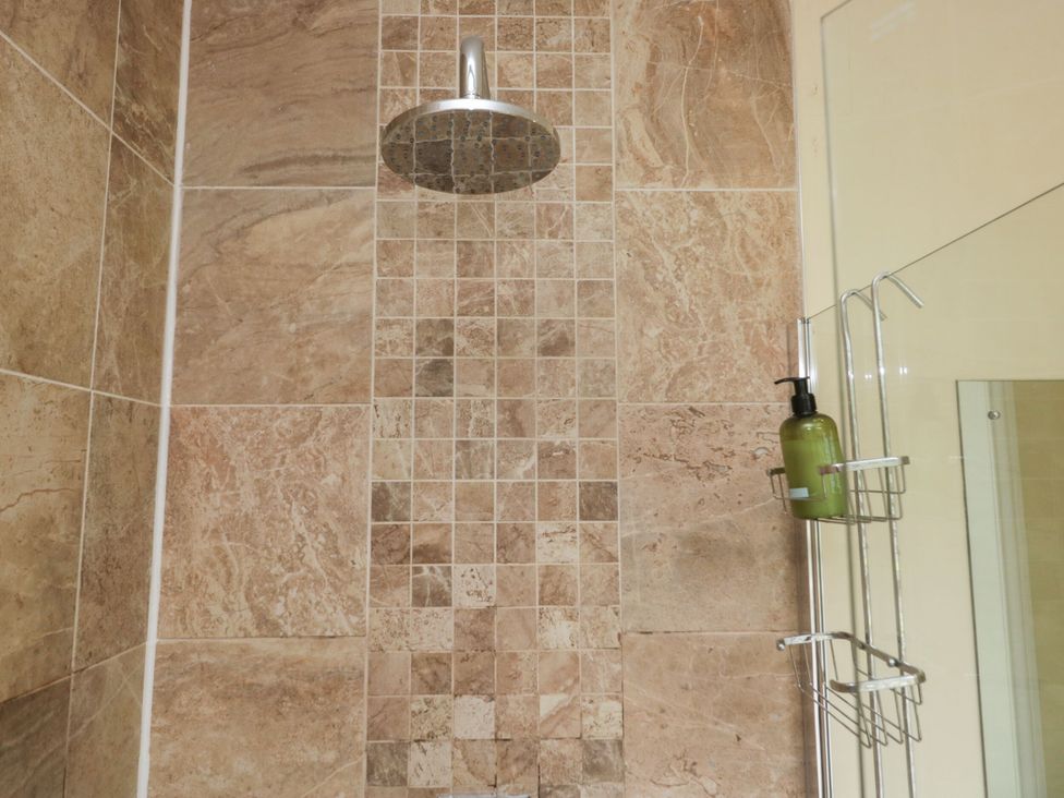 A shower with tiled wall and soap dispenser at Coleridge in Ambleside