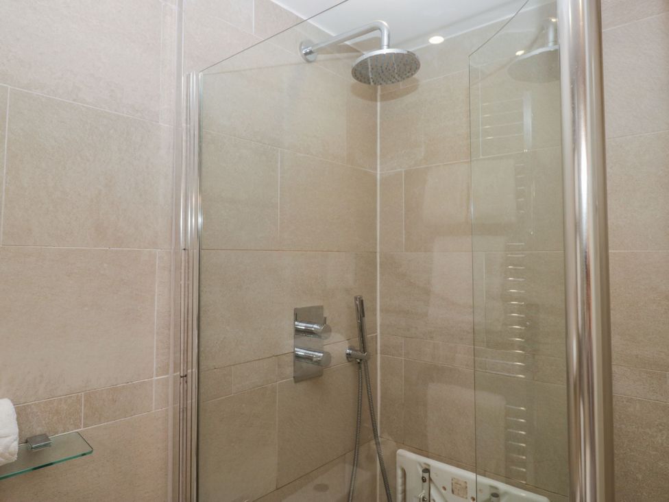 A shower with a glass enclosure and controls at Dorothy in Ambleside