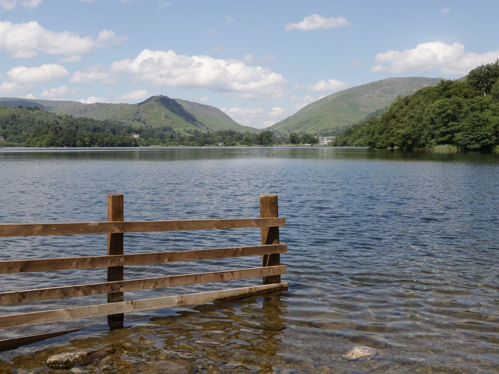 A lake with a wooden fence and mountains in the background at Dorothy in Ambleside