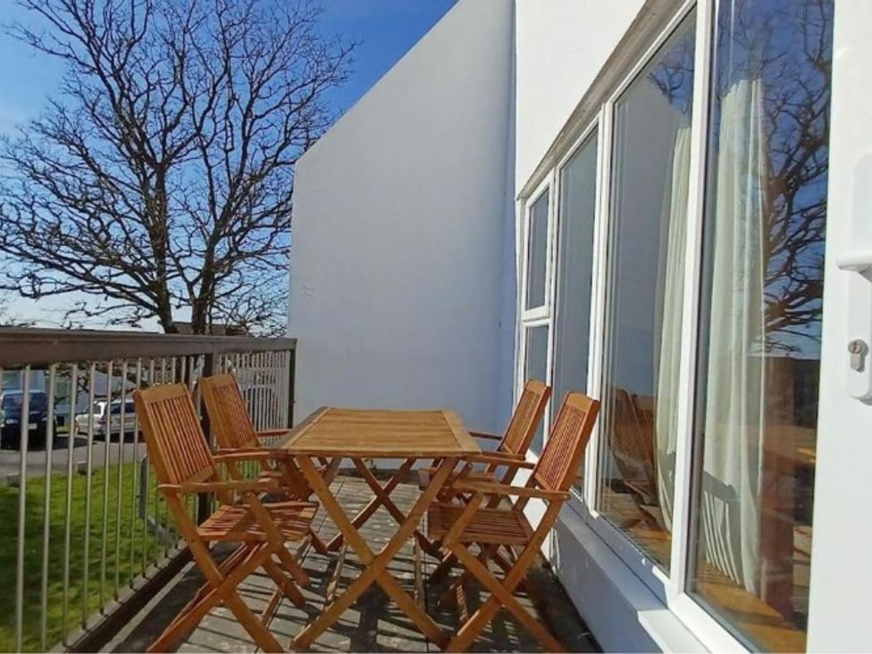 An outdoor patio with a wooden table and chairs at an unknown property