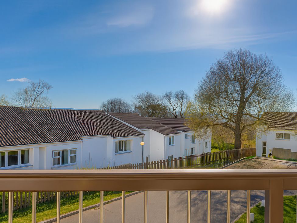 A view of houses and trees from a balcony at 21 Tamar & St. Anns Cottages Honicombe Park near St. Ann's Chapel, Cornwall