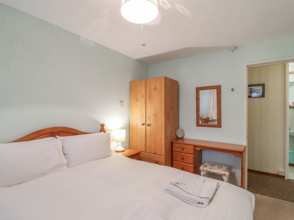 A bedroom with a bed, wardrobe, desk and mirror at 21 Tamar & St. Anns Cottages, Honicombe Park near St. Ann's Chapel, Cornwall