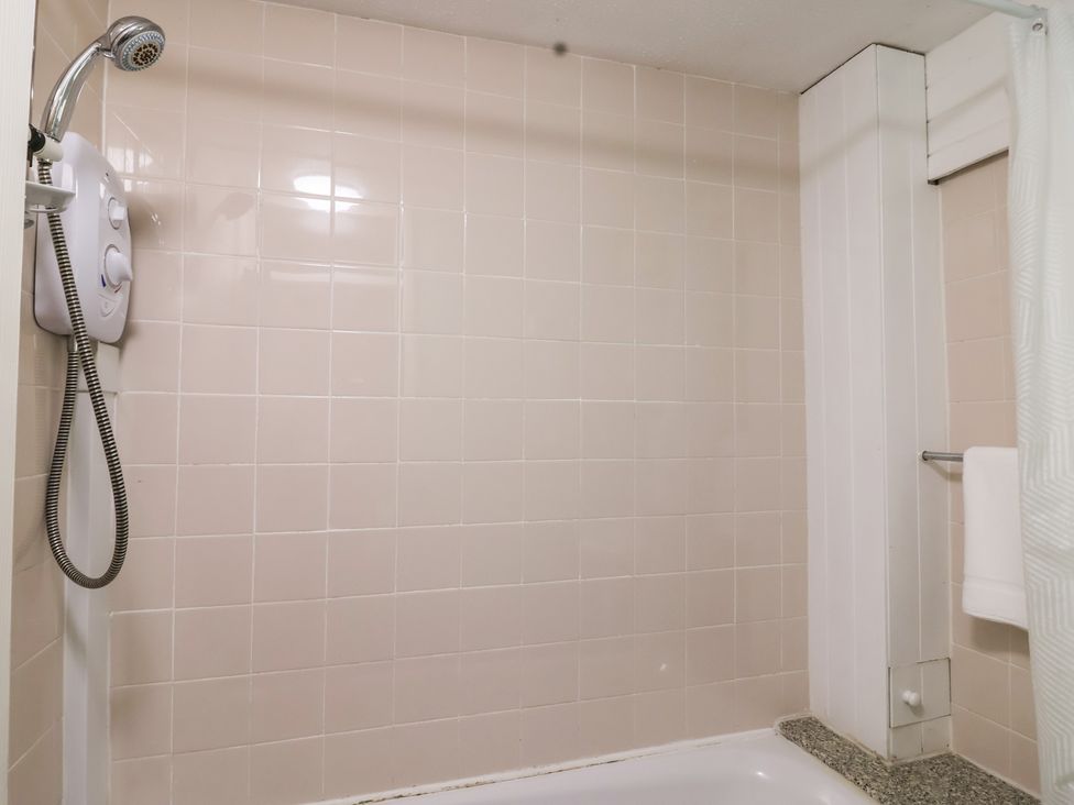 A bathroom with shower and towel on rack at 21 Tamar & St. Anns Cottages, Honicombe Park near St. Ann's Chapel, Cornwall